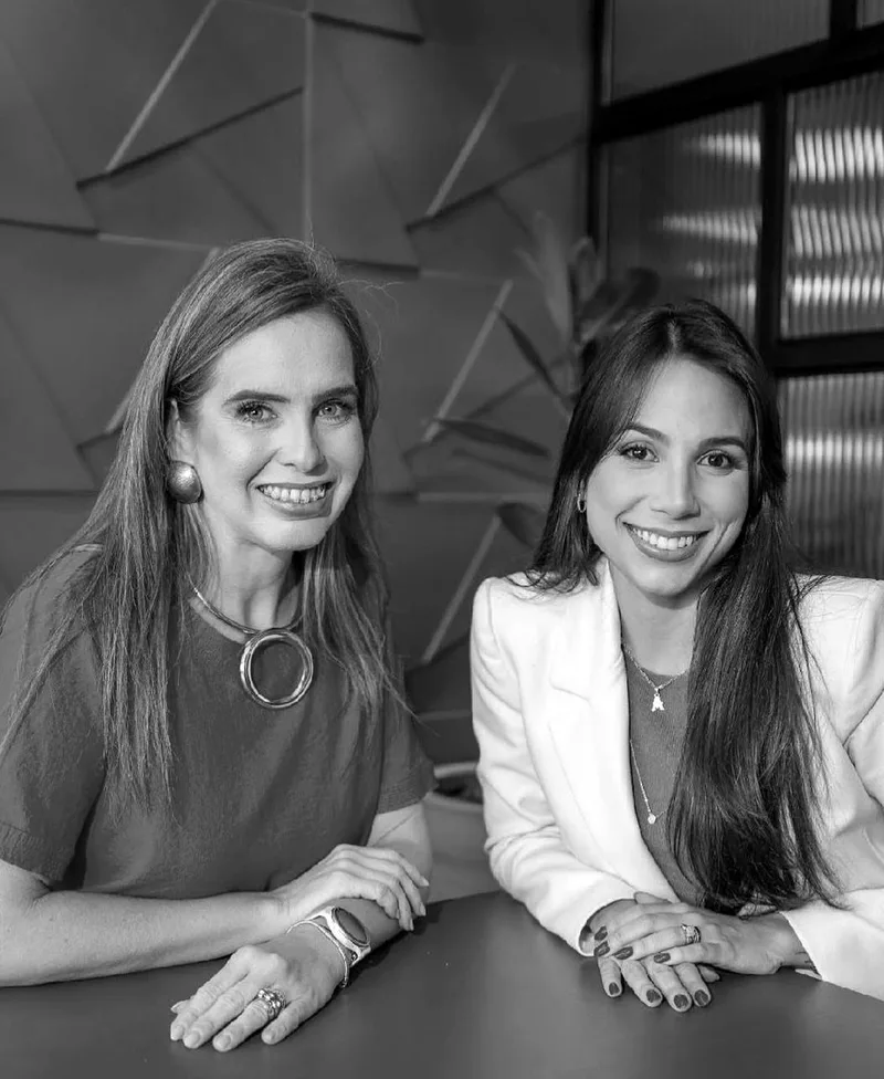 Anna Rachel e Nevita Luna sorrindo no escritório, em fotografia preto e branco